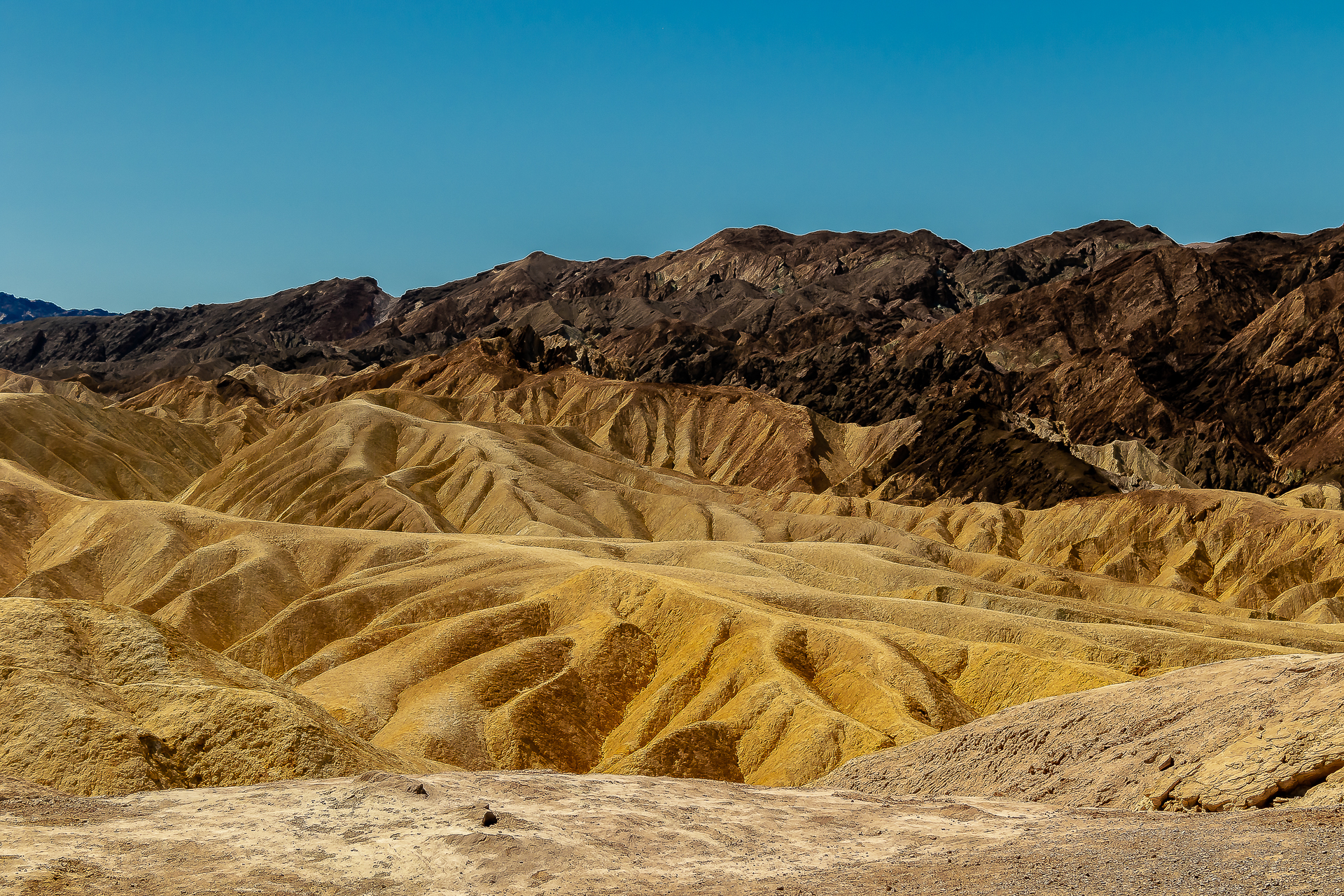 Death Valley desert road winding through layered ochre hills